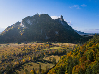 Ettaler Weidmoos autumn aerial with the Ammer River, Kofel and Rappenkopf under clear blue sky; warm valley tones, tranquil mood, ideal for travel ads.
