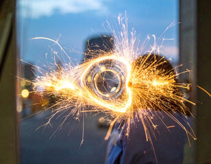 Sparkling firework is handheld in front of a reflective glass