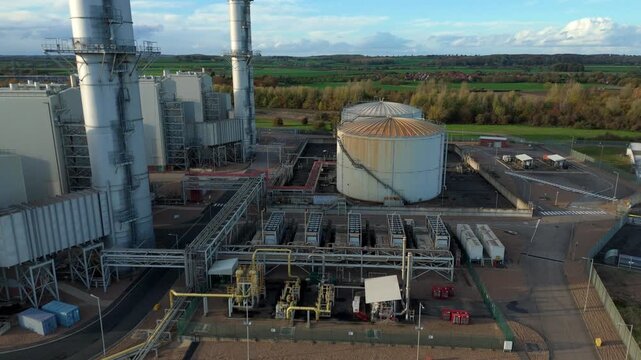 Aerial drone reveal shot of industrial fuel storage silos, pipework linked to large power plant energy generation electrical from oil fuel, Newark-on-Trent, United Kingdom 