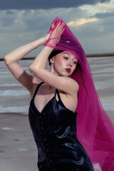 A girl with a red shawl poses against a natural backdrop