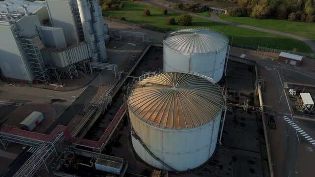 Aerial drone reveal shot of industrial fuel storage silos, pipework linked to large power plant energy generation electrical from oil fuel, Newark-on-Trent, United Kingdom 
