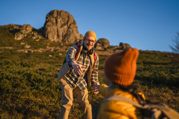 Fototapeta premium Father helping child on mountain hike reaching hand