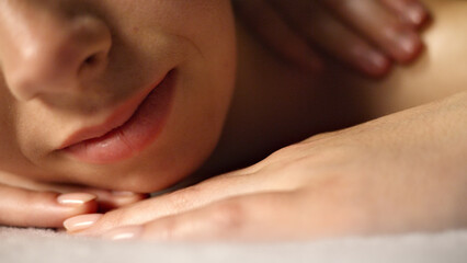 A woman receives a relaxing massage, her face serene. The masseuse's gentle touch and the tranquil...