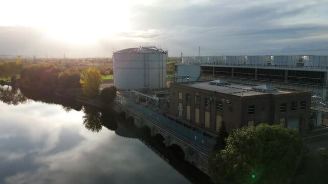 Aerial drone footage of fuel storage silos, cooling water intakes and turbine cooling for huge industrial power plant at sunset, golden light, Newark-on-Trent, United Kingdom 