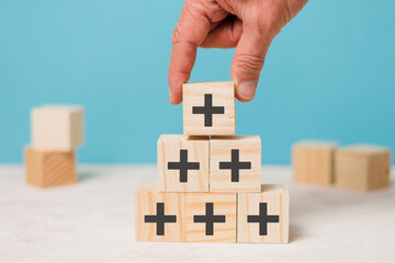 Positive things; added value, benefits, additional, personal development, growth mindset, positive thinking, opportunities, emerging market. Putting the cubes with plus sign to offer positive things.