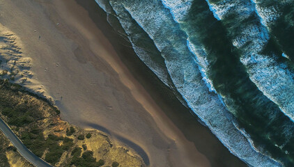 Top aerial drone photo showing a stunning view of the Atlantic coastline in Portugal with turquoise sea waves, sandy beach and rugged rocks from different angle, cut and perspective.