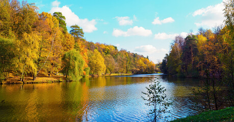 Stunning autumn landscape with forest and pond in the park - panorama