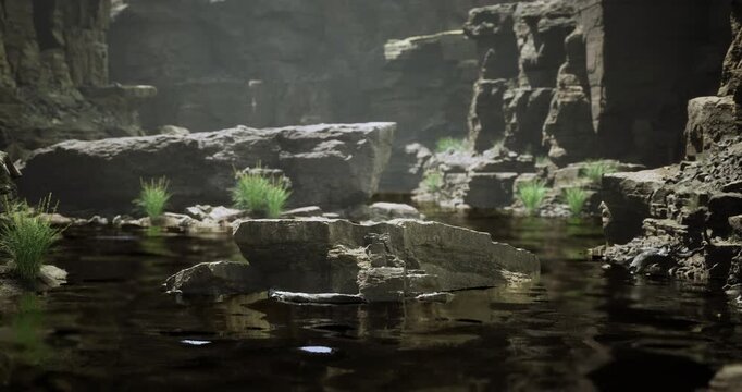 Gentle ripples dance across the dark water of a serene canyon. Sunlight softly illuminates rocky cliffs, while patches of green grass peek through the stones, revealing natures harmony.