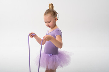 Young ballerina with cochlear implant looking at rope in her hands. Copy space. Symbol of awareness, concentration, and childhood inclusion through art and technology.