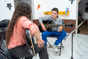 Young boy watching his guitar teacher closely while learning technique during a private lesson. Concept of focused learning, music education, and instrumental skill development
