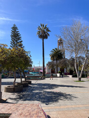 Fototapeta premium Ambrosio O’Higgins Square in Vallenar, Chile. Small town in the Huasco Valley, in Atacama Region. Main Square with palm trees, benches, church and people walking around.