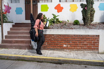 Guitar teacher leaving the classroom after finishing her private lessons, carrying her instrument and materials. End of workday, education, music teaching, professional lifestyle