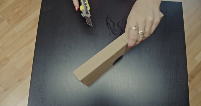 Watch as skilled hands carefully cut a cardboard tray with a utility knife on a table. The video captures an action, highlighting the satisfying scratching sounds of the blade against the material.