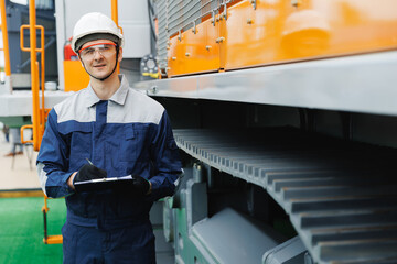 Young Caucasian male engineer with clipboard inspecting drilling mining truck in industrial facility