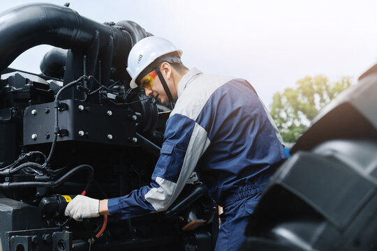 Young Caucasian male engineer inspecting diesel engine from industrial mining truck equipment