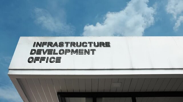 Infrastructure Development Office word sign clearly displayed on the official government building facade beneath a clear blue sky, signifying the agency responsible for planning, executing