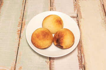 A trio of round Colombian almojabanas on a white plate