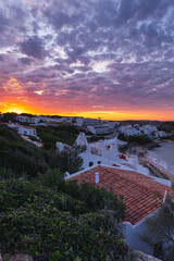 Stunning sunset over the bay of Arenal d'en Castell, Menorca. Vibrant colors reflected in the sea.