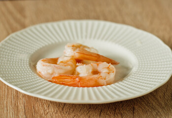 A small pile of fresh, cooked pink shrimp on a stylish, textured white plate