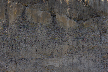 Close-up of a rough, weathered, and cracked concrete wall surface showing detailed texture, aggregate, and signs of aging and decay.