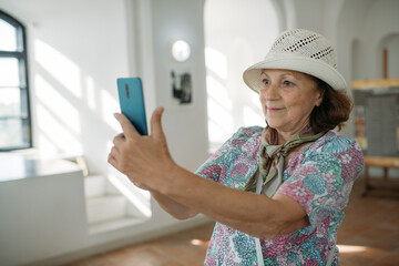 An elderly woman conducts a guided tour of an ancient castle. The pensioner examines historical artifacts at the exhibition, takes pictures on the phone