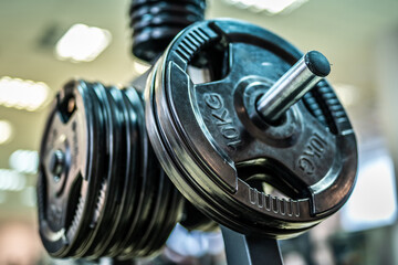 Close up gym weight plates. Stack of round metal weight plates on gym bar in fitness studio.