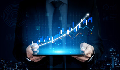 A business professional in a suit holds a digital tablet displaying vibrant financial graphs showcasing growth trends and data analytics in an office at night. Impute