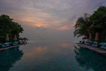 Naklejka premium Tranquil closeup calm sea water waves with palm trees. Reflection on pool. Tropical island beach landscape exotic shore coast. Summer vacation, holiday amazing nature. Relax paradise, Maldives.