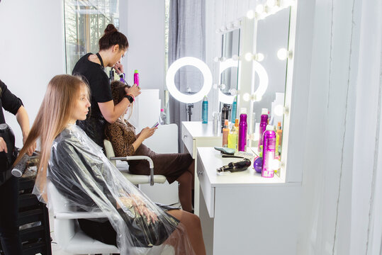 Hairdresser brushing long blonde hair with brush in beauty salon - Powered by Adobe