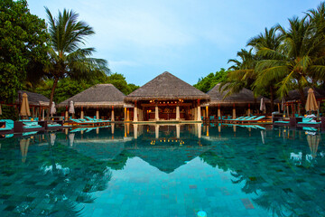 Tranquil closeup calm sea water waves with palm trees. Cabins with pool. Tropical island beach landscape exotic shore coast. Summer vacation, holiday amazing nature. Relax paradise, Maldives.
