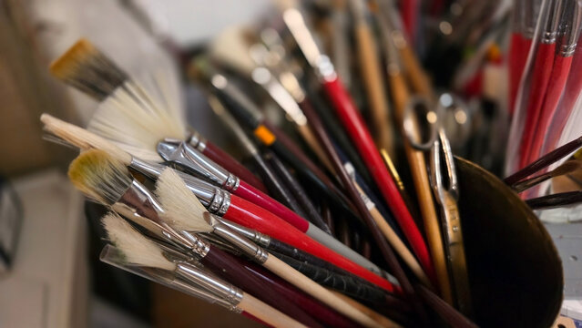 Creative workspace with assorted paintbrushes in an artist's studio. Close-up