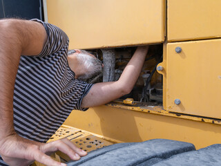 Skilled technician inspecting and fixing the engine of an excavator or heavy machinery. Focusing on maintenance and diagnostics