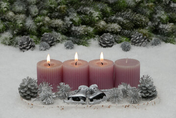 Third Advent: Decoration with four pink Advent candles, fir branches and Christmas baubles in the snow with space for text.
