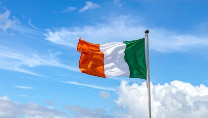"Irish flag waving on a tall flagpole against a bright blue sky with scattered clouds