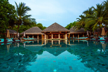 Tranquil closeup calm sea water waves with palm trees. Cabins near pool. Tropical island beach landscape exotic shore coast. Summer vacation, holiday amazing nature. Relax paradise, Maldives.