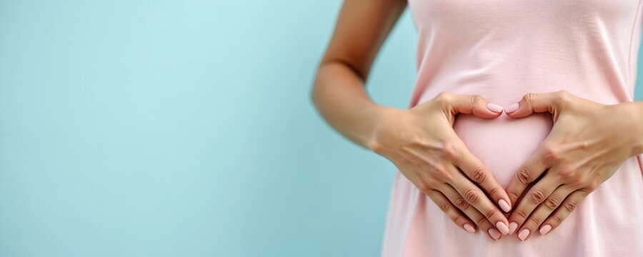 Woman forms heart shape on her belly with hands. This symbolizes love, maternal care, and healthy gut or digestion. Focus on well being and body positivity.
