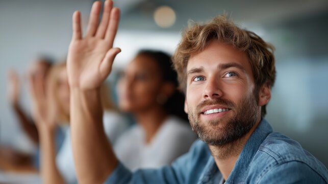 Group of professionals in a modern meeting room, with a smiling man raising his hand, engaged in discussion and seeking to contribute to the collaborative environment