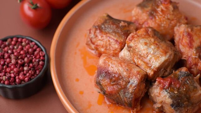 Hake fish cooked in pieces in tomato sauce, stew with peppers and carrots. Hake fish in tomato sauce as a food background for your design.