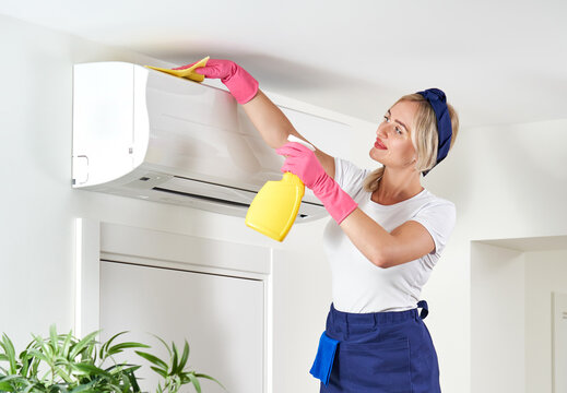 Woman cleaning air conditioner with rag. Cleaning service or housewife concept