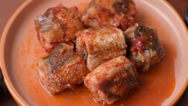Hake fish cooked in pieces in tomato sauce, stew with peppers and carrots. Hake fish in tomato sauce as a food background for your design.