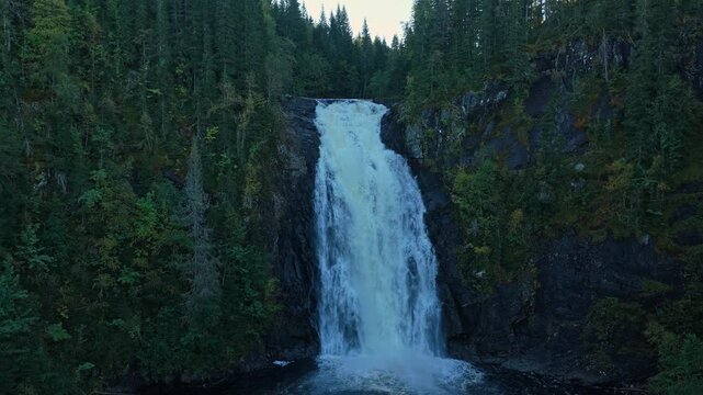 Drone view of mighty waterfall cascading over rugged cliff in Norway