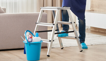 Cropped view of man climbing ladder to clean ceiling. Cleaning service concept