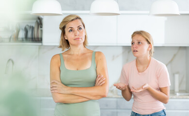 Agitated daughter imploringly asks angry mother for forgiveness. Concept of child rearing,...