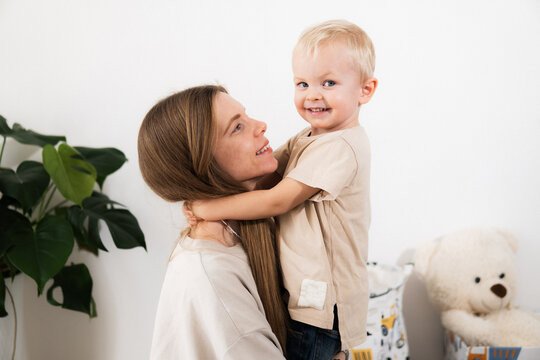 A happy mother with children at home is family happiness and care. A warm family scene of a blonde haired girl and two children sitting on the floor in a cozy room