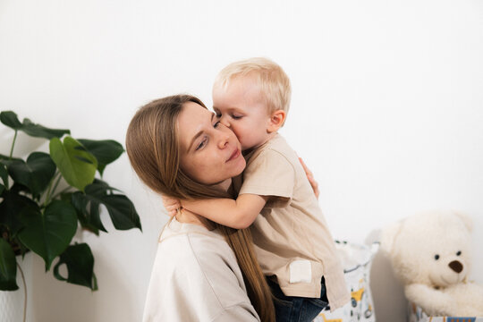 A happy mother with children at home is family happiness and care. A warm family scene of a blonde haired girl and two children sitting on the floor in a cozy room