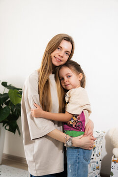 A happy mother with children at home is family happiness and care. A warm family scene of a blonde haired girl and two children staying on the floor in a cozy room