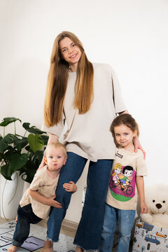 A happy mother with children at home is family happiness and care. A warm family scene of a blonde haired girl and two children staying on the floor in a cozy room