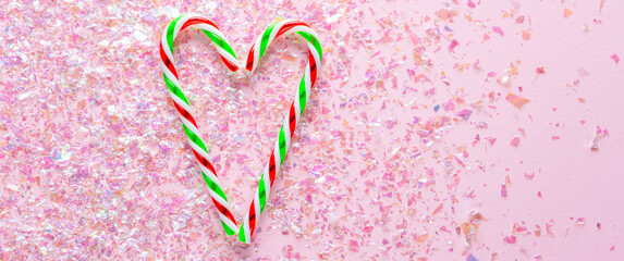 two lollipops in heart shape on pink background with glitter. Gifts for the New year and Christmas. top view