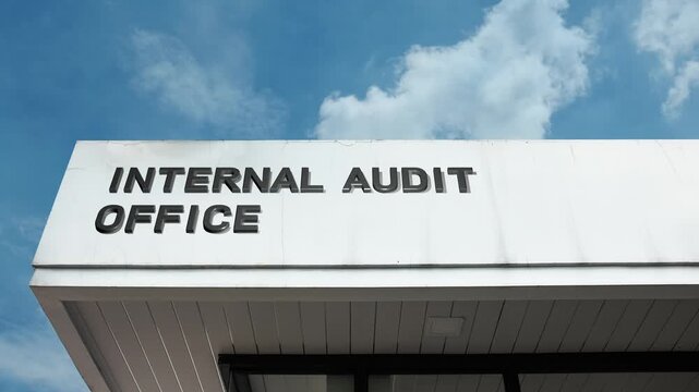 Internal Audit Office word sign clearly displayed on the corporate or government building facade beneath a clear blue sky, signifying the department responsible for evaluating an organization's