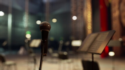 A microphone stands ready on stage, surrounded by music stands and empty chairs. The atmosphere is filled with anticipation as the show approaches in the elegant theater.